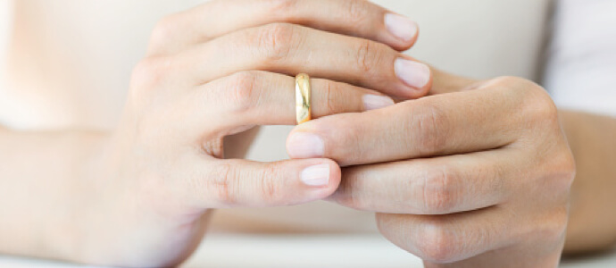 person pulling wedding ring off of their right ring finger divorce