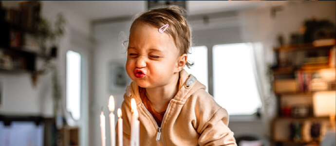 little girl blowing out birthday candles in a pink sweatshirt child support