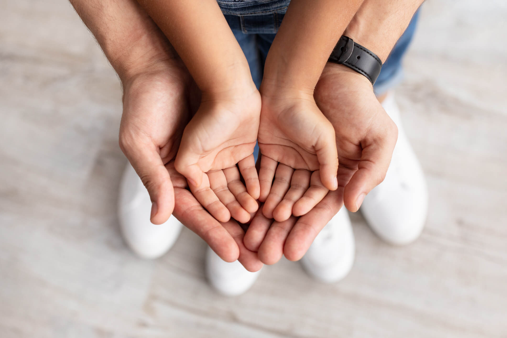 Care, Support And Growth. Cropped close up above top view of caring man holding girl's palms in hands, spending free time with daughter together at home. Children Custody Concept