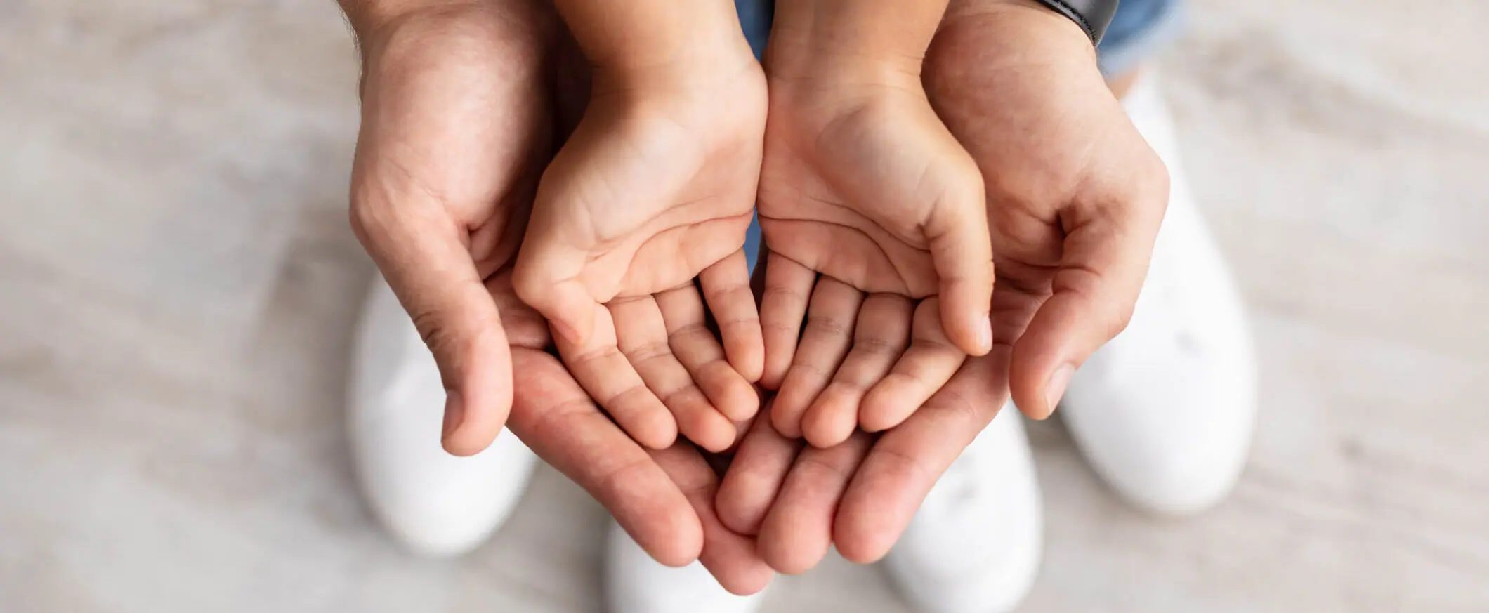 Care, Support And Growth. Cropped close up above top view of caring man holding girl's palms in hands, spending free time with daughter together at home. Children Custody Concept