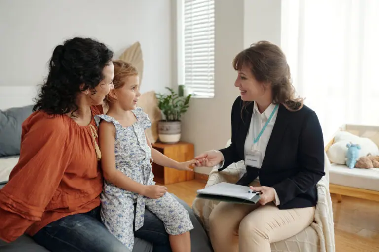 A young girl and a woman with curly dark hair sit on a couch